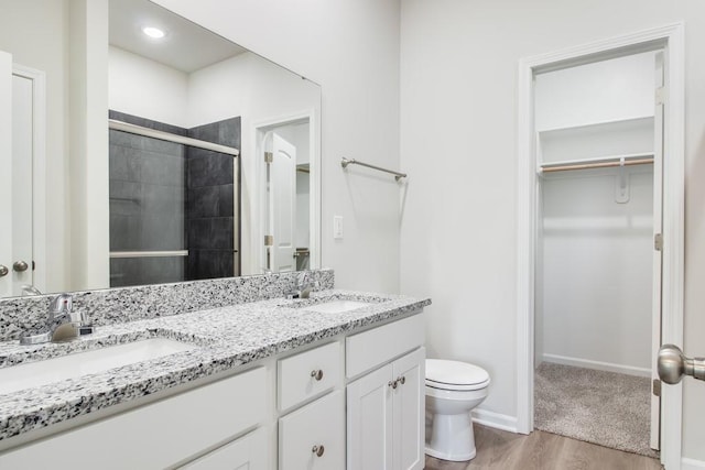 bathroom with vanity, wood-type flooring, toilet, and a shower with shower door