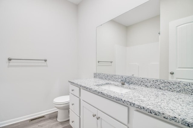 bathroom with wood-type flooring, walk in shower, vanity, and toilet