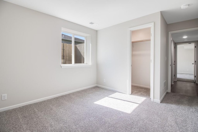 unfurnished bedroom with carpet flooring, a closet, and a spacious closet