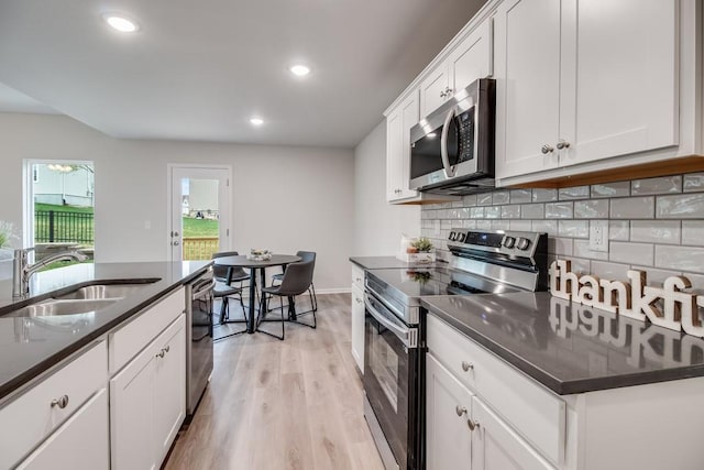 kitchen with tasteful backsplash, stainless steel appliances, sink, and white cabinets