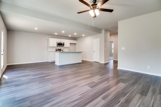 unfurnished living room featuring dark hardwood / wood-style floors and ceiling fan