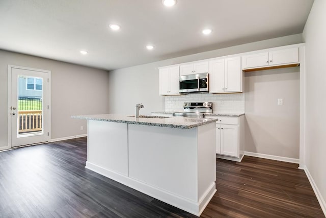 kitchen with sink, appliances with stainless steel finishes, tasteful backsplash, an island with sink, and white cabinets