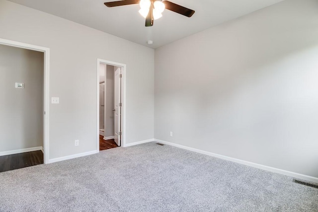 unfurnished bedroom featuring dark colored carpet, connected bathroom, and ceiling fan