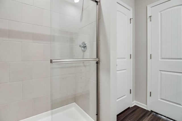 bathroom featuring a shower with door and wood-type flooring