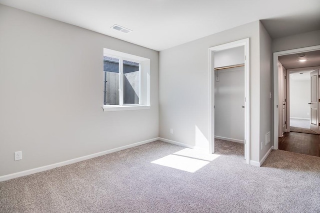 unfurnished bedroom with a spacious closet, carpet floors, and a closet