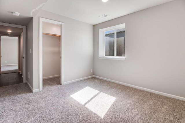 unfurnished bedroom with a spacious closet, a closet, and carpet flooring