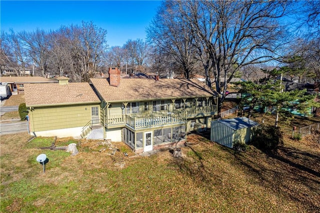 rear view of house featuring a sunroom, a storage shed, and a yard