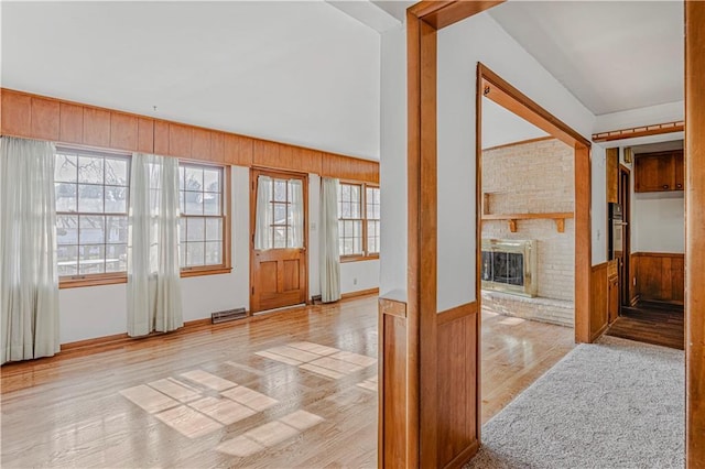 entryway with wood walls, a fireplace, and light hardwood / wood-style floors