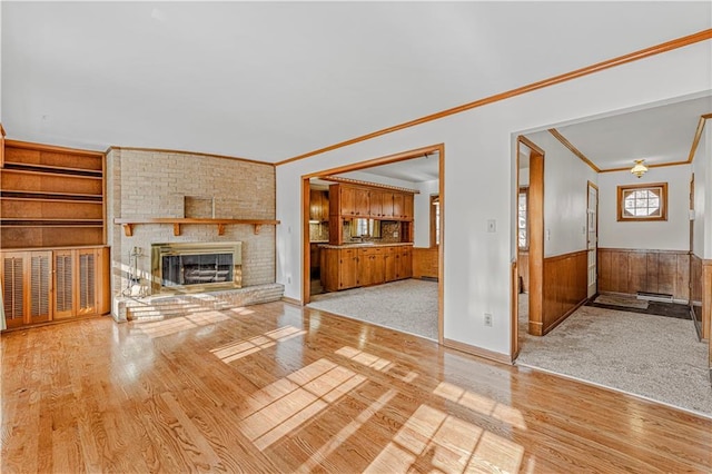 unfurnished living room featuring a fireplace, light hardwood / wood-style floors, and crown molding