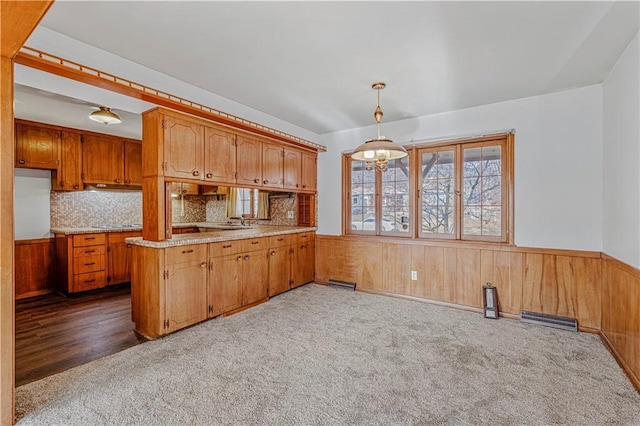 kitchen with dark colored carpet, backsplash, decorative light fixtures, and kitchen peninsula