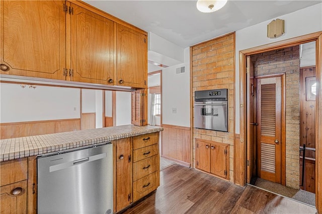 kitchen with wood walls, dark hardwood / wood-style flooring, and stainless steel appliances