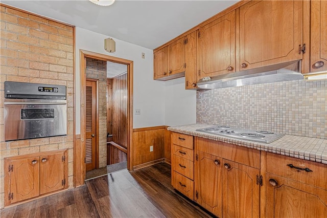 kitchen featuring wood walls, oven, dark hardwood / wood-style floors, and white stovetop