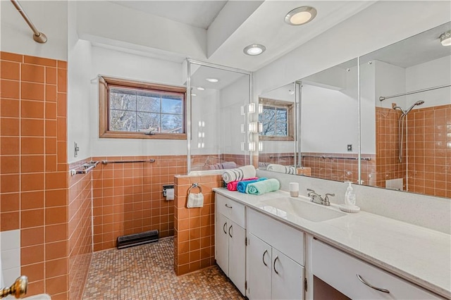 bathroom featuring a tile shower, tile patterned flooring, vanity, and tile walls