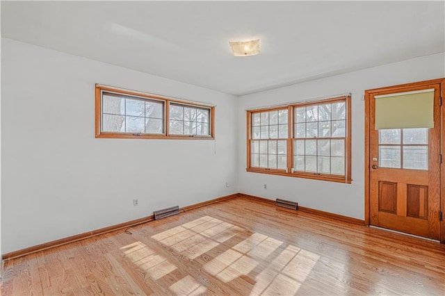 empty room with a wealth of natural light and light hardwood / wood-style floors