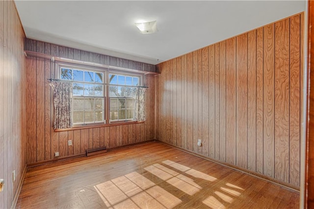 empty room with wood walls and light hardwood / wood-style floors