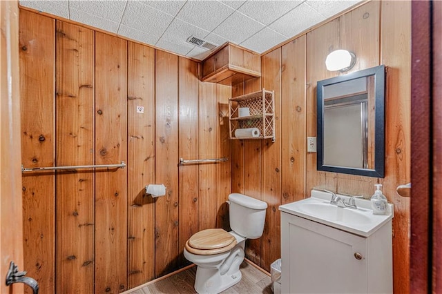 bathroom featuring wooden walls, toilet, vanity, and hardwood / wood-style flooring