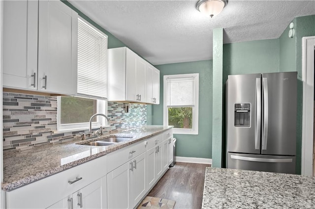 kitchen featuring stainless steel refrigerator with ice dispenser, tasteful backsplash, sink, and white cabinets