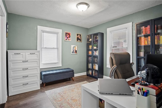 home office featuring dark wood-type flooring and a textured ceiling