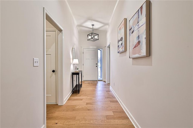 hall featuring a chandelier, light wood-type flooring, and ornamental molding