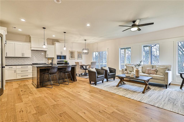 living room featuring sink, ceiling fan, and light hardwood / wood-style floors