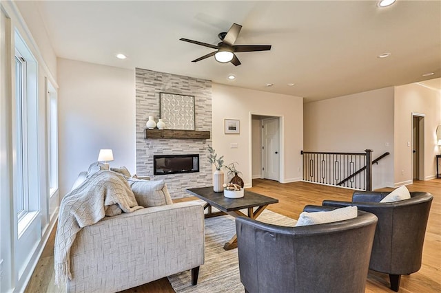 living room featuring light hardwood / wood-style flooring, a fireplace, and ceiling fan