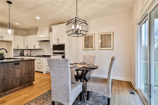 dining area with sink, an inviting chandelier, and light wood-type flooring