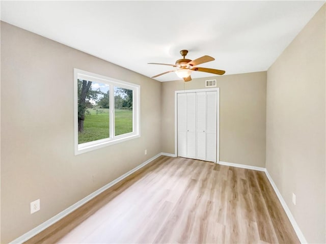 unfurnished bedroom featuring a closet, light hardwood / wood-style flooring, and ceiling fan