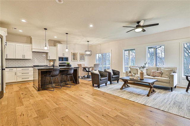 living room featuring light hardwood / wood-style floors, sink, and ceiling fan