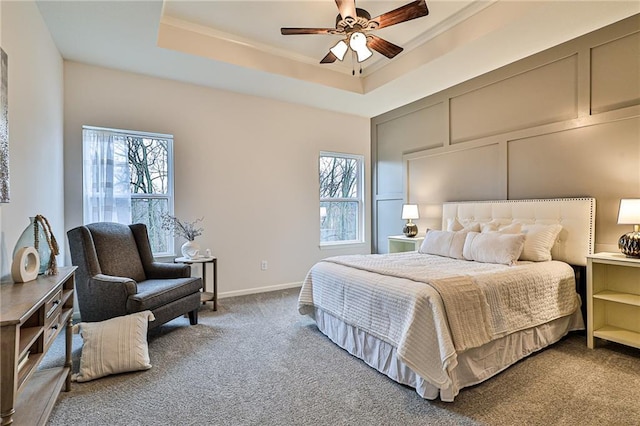 carpeted bedroom featuring ceiling fan and a tray ceiling