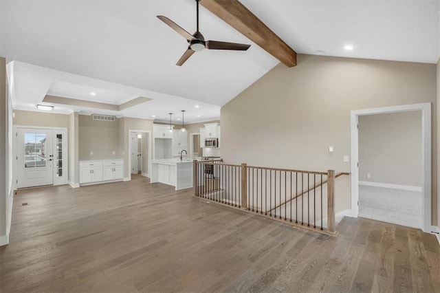 unfurnished living room with vaulted ceiling with beams, ceiling fan, sink, and wood-type flooring