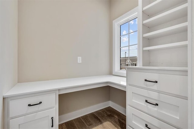 unfurnished office featuring built in desk and dark wood-type flooring