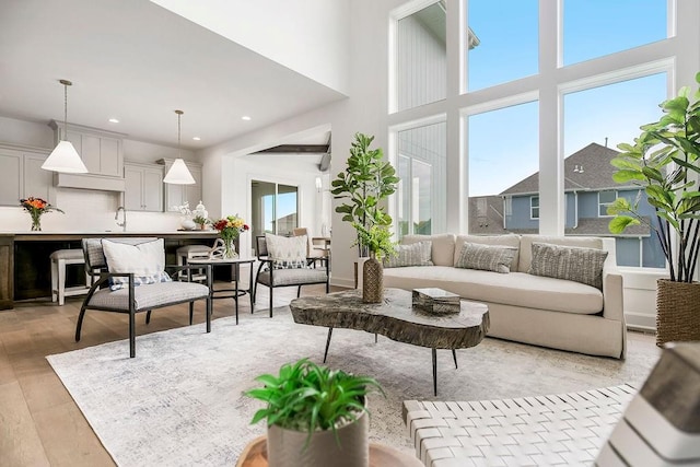 living room with sink, light hardwood / wood-style flooring, and a high ceiling