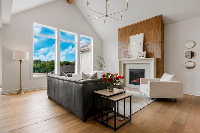 living room featuring a notable chandelier, light hardwood / wood-style flooring, a tile fireplace, and high vaulted ceiling