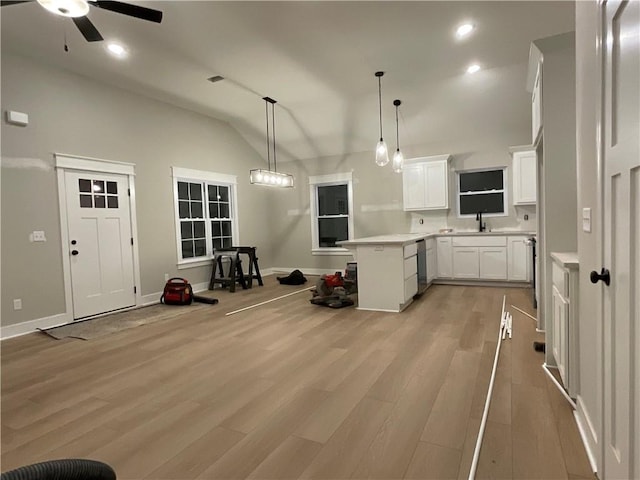 kitchen featuring sink, decorative light fixtures, vaulted ceiling, kitchen peninsula, and white cabinets