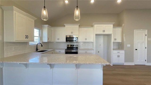 kitchen featuring a peninsula, appliances with stainless steel finishes, light stone counters, and a sink