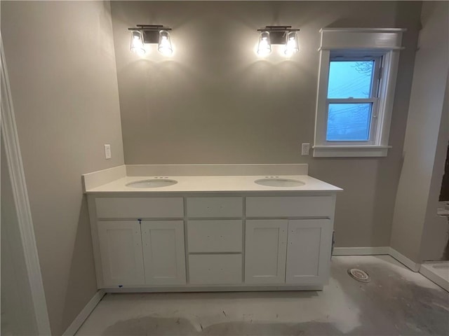 full bathroom with double vanity, a sink, and baseboards