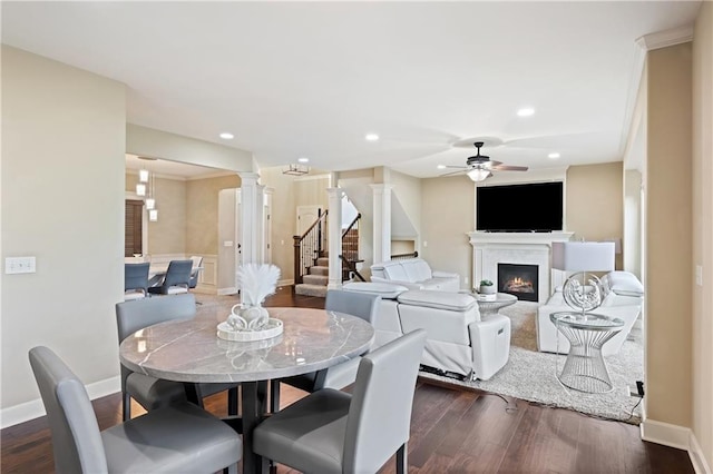 dining area with decorative columns, ceiling fan, a fireplace, and dark hardwood / wood-style flooring