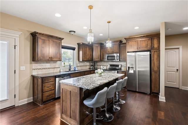 kitchen featuring appliances with stainless steel finishes, hanging light fixtures, dark hardwood / wood-style flooring, and a kitchen island