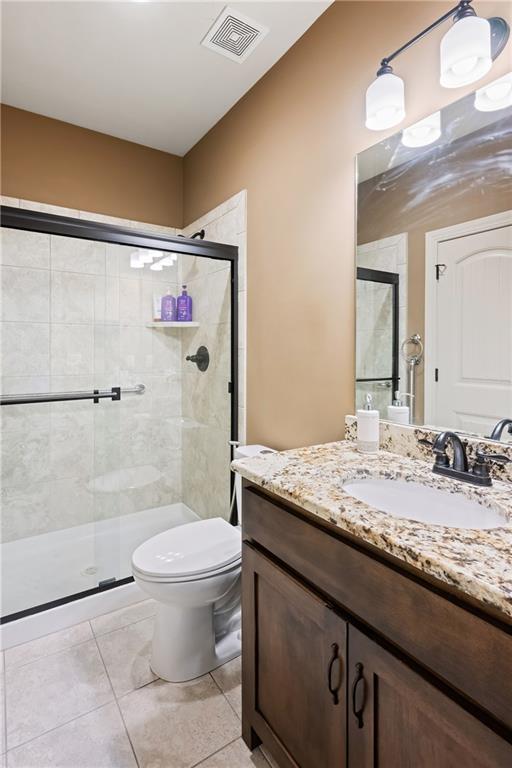 bathroom with vanity, tile patterned flooring, toilet, and an enclosed shower