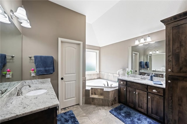 bathroom with vanity, tiled bath, and vaulted ceiling