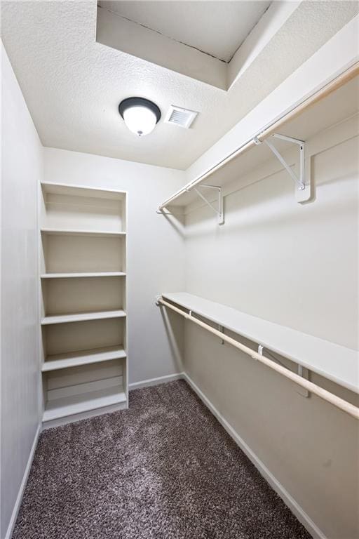 spacious closet featuring dark colored carpet