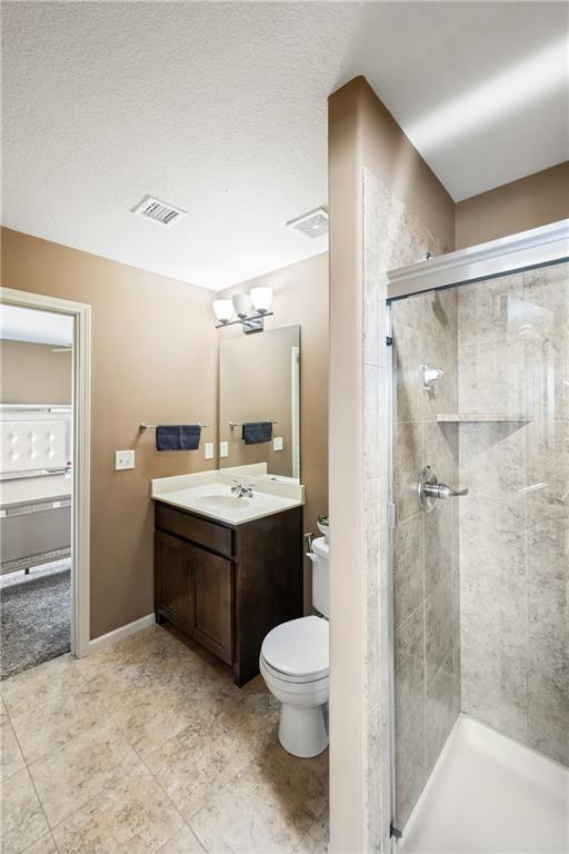 bathroom featuring walk in shower, vanity, toilet, and a textured ceiling