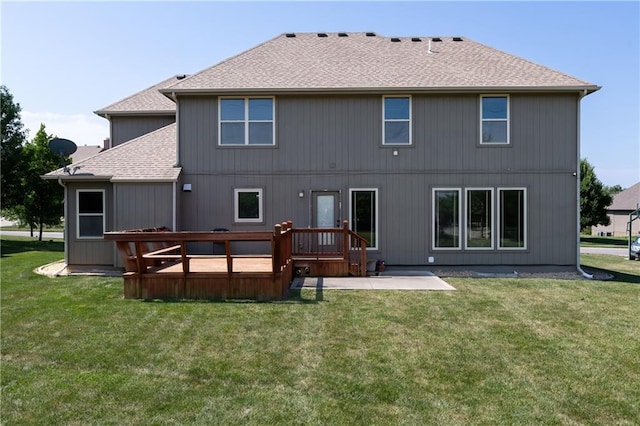 rear view of property featuring a lawn, a wooden deck, and a patio area