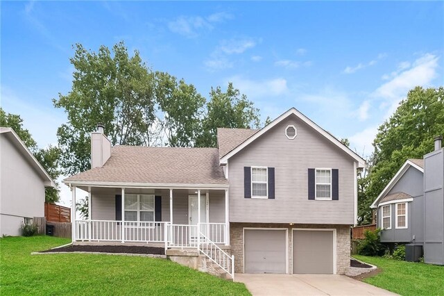 split level home with a garage, a porch, central air condition unit, and a front yard