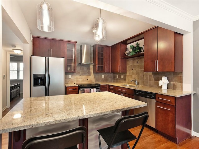 kitchen with wall chimney range hood, light hardwood / wood-style floors, stainless steel appliances, and backsplash