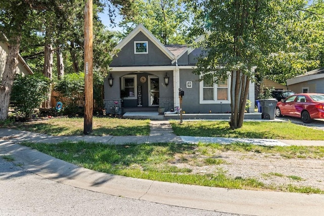 bungalow-style home featuring covered porch and stucco siding