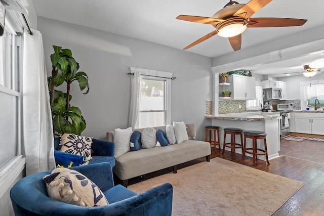 living room with dark wood-type flooring, a wealth of natural light, and a ceiling fan