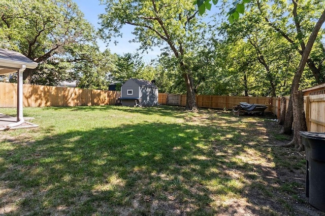 view of yard featuring an outbuilding, a storage unit, and a fenced backyard