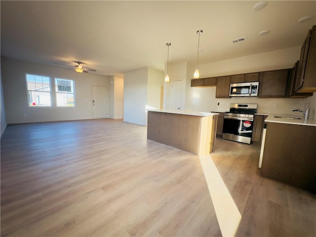 kitchen featuring ceiling fan, a center island, stainless steel appliances, and light hardwood / wood-style flooring