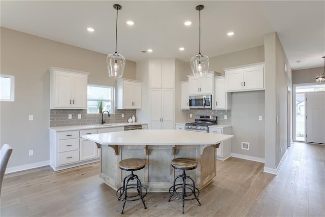 kitchen with sink, a center island, appliances with stainless steel finishes, and white cabinetry